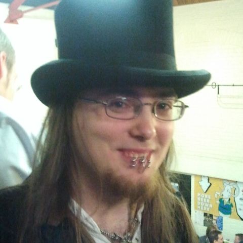 A man with long hair and glasses in a tall black top hat