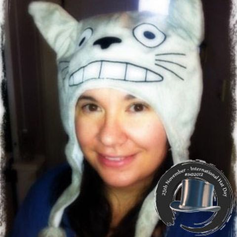 A smiling woman in a cuddly grey Totoro hat, with the 2012 logo