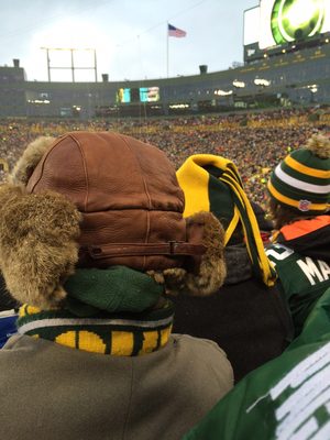 Fans in winter hats watching a football game in a stadium