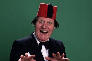 A comedian in a red fez pulling a surprised face