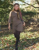 A woman in a knitted hat walking through autumn leaves
